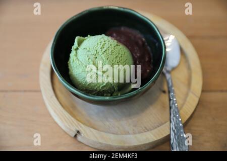 Japanese green tea ice cream with red bean topping on wooden table in coffee shop Stock Photo