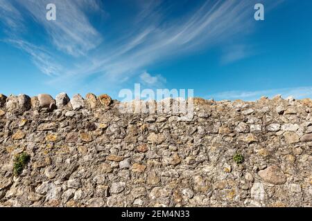 Boundary wall made of stones and concrete in the countryside with blue sky and clouds on background. Verona province, Veneto, Italy, Europe. Stock Photo