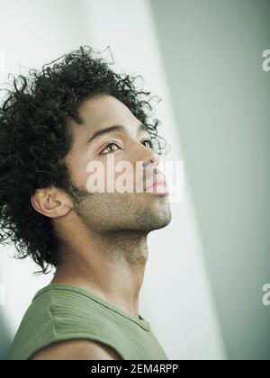 Side profile of a young man leaning against a wall and thinking Stock Photo