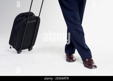 Low section view of a man standing with a suitcase Stock Photo