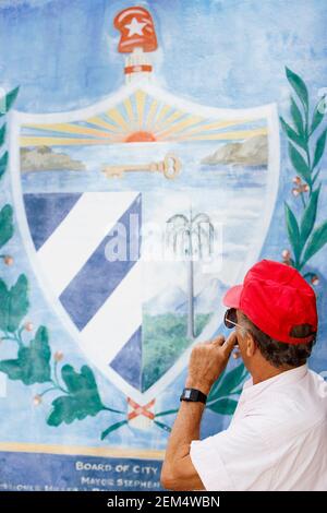 High angle view of a mature man smoking a cigar and looking at a mural on the wall Stock Photo