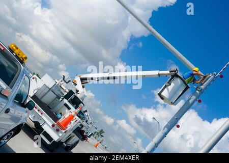 Low angle view of a maintenance engineer on a mobile crane repairing a security camera on a pole Stock Photo