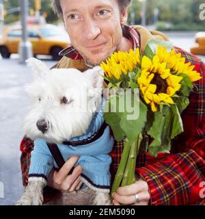 Close-up of a mature man holding a bunch of flowers and a dog Stock Photo