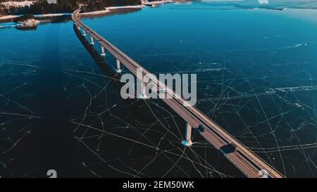 Traffic driving on a bridge over a bay covered in clear thick ice. Stock Photo