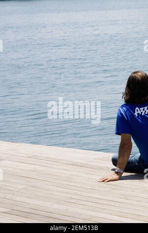 Rear view of a man sitting at the riverside, Barcelona, Spain Stock Photo