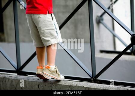 Low section view of a boy leaning against a railing Stock Photo