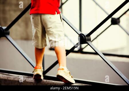 Low section view of a boy leaning against a railing Stock Photo