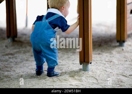 Rear view of a boy peeking under a wooden structure, Madrid, Spain Stock Photo