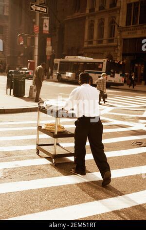 Rear view of a waiter pushing a serving trolley on the road, New York City, New York State, USA Stock Photo