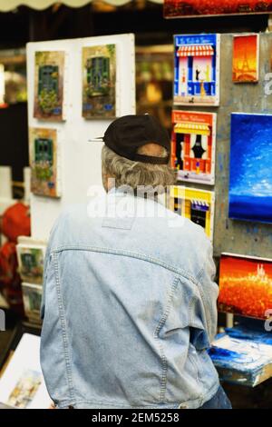 Rear view of a person standing in front of paintings Stock Photo