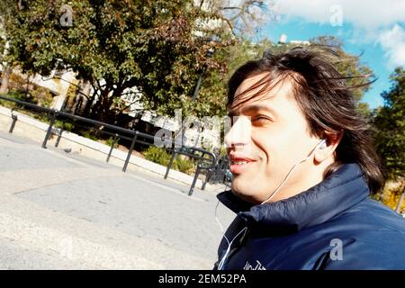 Side profile of a young man listening to music and smiling Stock Photo