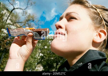 Close-up of a young woman eating a chocolate bar Stock Photo