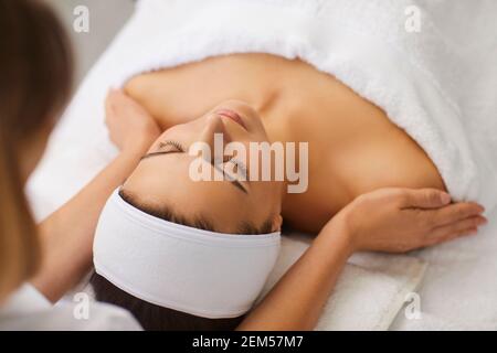 Cosmetologist or masseur making manual relaxing rejuvenating massage for face and shoulders for woman Stock Photo