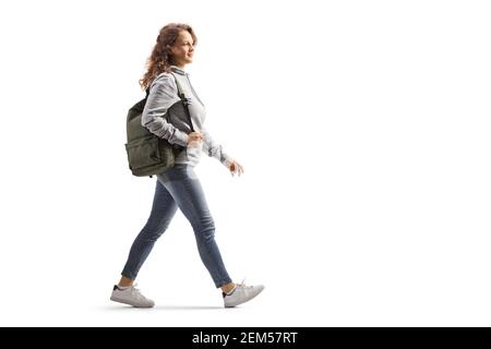 Full length profile shot of a female student in jeans with a backpack walking isolated on white background Stock Photo