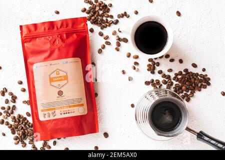 Tiraspol, Moldova - February 12, 2021: red coffee bag with degassing valve, cup of coffee, coffee beans, cezve, top view. 100% Arabica, Barista Coffee Stock Photo