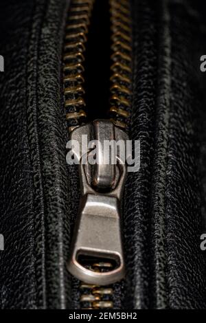 Detail of locking zipper on black leather jacket. Close up macro local focus shot. Vertical macro photography view. Stock Photo