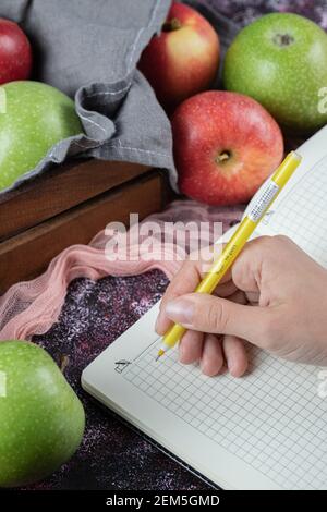 Green, red apples and a blank recipe book on the table Stock Photo