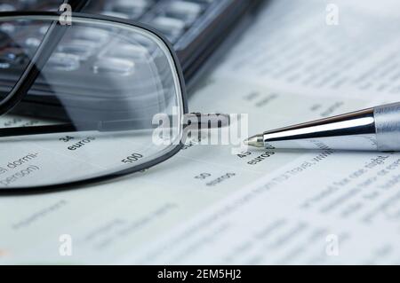 Glasses, calculator and pen lie on a newspaper Stock Photo