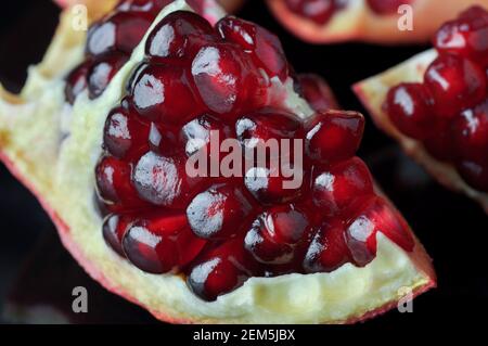 Juicy ripe pomegranates seeds close up. Several ripe pomegranate fruits and an open pomegranate Stock Photo
