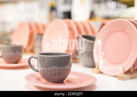 Commercial pink and white plates and bowls stacked with crystal wine glasses.Colorful ceramic clean dishware.Ceramic crockery tableware Stock Photo