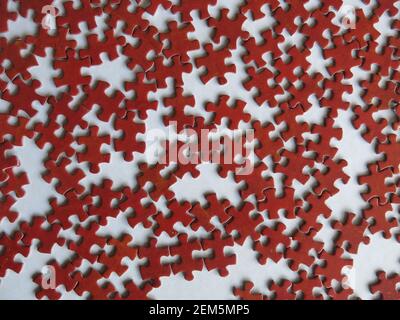 A mass of jigsaw pieces laid out on the table that all look the same shape and colour of red. Stock Photo