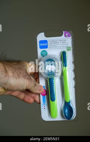 Paris, France - Nov 16, 2018: POV male hand holding looking at the new unpackaged Mam baby spoon made from plastic Stock Photo