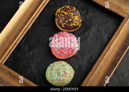 Sweet small doughnuts with sprinkles on a black background Stock Photo