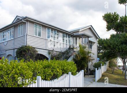 Typical Queensland house with tropical foliage and white picket fence on overcast day in Australia Stock Photo