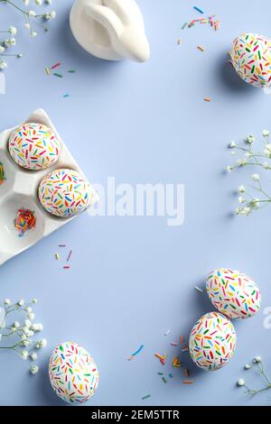 Happy Easter flat lay composition. Colorful Easter eggs, Easter bunny, flowers on blue background. Top view, overhead. Stock Photo