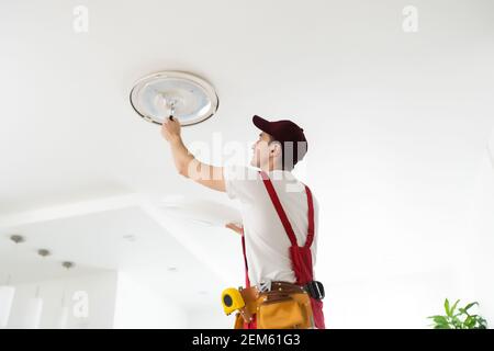Electrician installs a chandelier on the ceiling. Construction concept Stock Photo