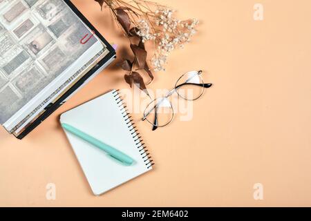 Books, notebook, pen and glasses on orange background Stock Photo