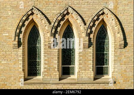 A set of leaded glass  windows framed with brick details on a church in Ontario. Stock Photo