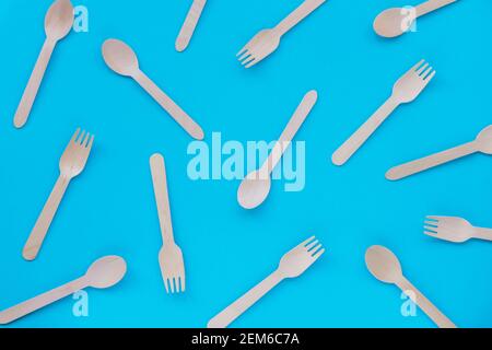 Texture of disposable bamboo spoons and forks on blue background. Zero waste concept. Top view, flat lay. Stock Photo