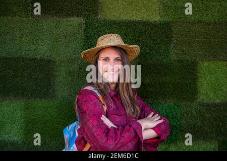 Portrait of a beautiful happy girl who wears a straw summer hat and is isolated on green grass background Stock Photo