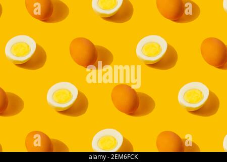 Farm chicken fresh and boiled half cut eggs pattern on yellow background. Healthy food or Happy Easter creative minimal concept. Flat lay, top view Stock Photo