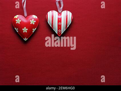 Two red and white metal hearts on a red paper background Stock Photo