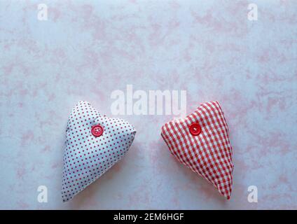 Two red and white fabric hearts on a pink marbled paper background Stock Photo