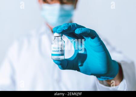 Doctor, nurse, scientist hand in blue gloves holding flu, measles, coronavirus, covid-19 vaccine disease preparing vaccination shot, medicine and drug Stock Photo