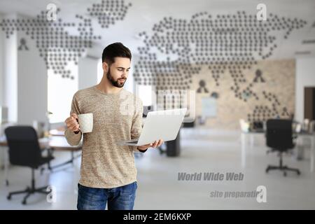 Male programmer with laptop and cup of coffee in office Stock Photo