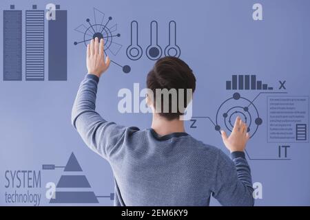 Male programmer using virtual screen on color background, back view Stock Photo