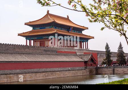Beijing, China - April 27, 2010: Moat, ramparts, and Red Gate of divine Prowess building as exit of Forbidden City North side under silver cloudscape. Stock Photo