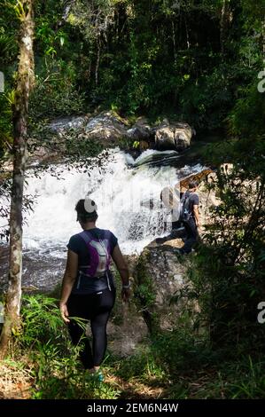 Hikers walking down towards the viewing spot of Paraibuna river waterfall in Serra do Mar estate park, Cunha nucleus. Stock Photo