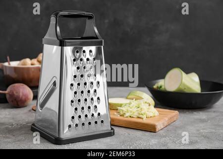 Metal grater and vegetables on dark background Stock Photo