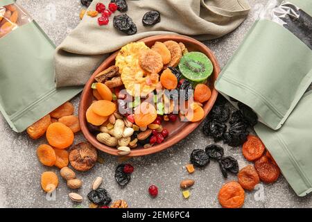 Plate and bags with different dried fruits and nuts on gray background Stock Photo