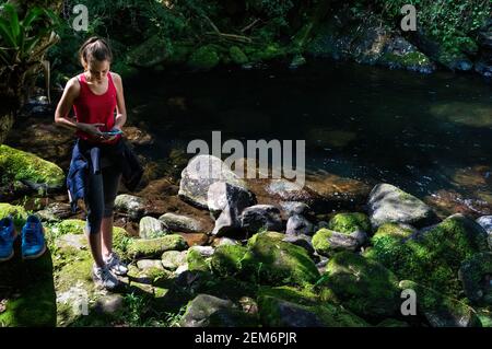 The natural pool formed by Ipiranguinha waterfall crystal clear waters with green vegetation and rocks around in Serra do Mar estate park. Stock Photo