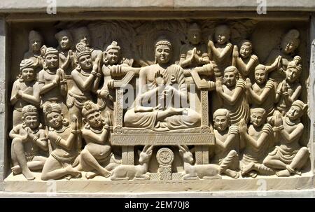 Close-up view of stone carving of Indian god Buddha on throne and being greeted by devotees Stock Photo