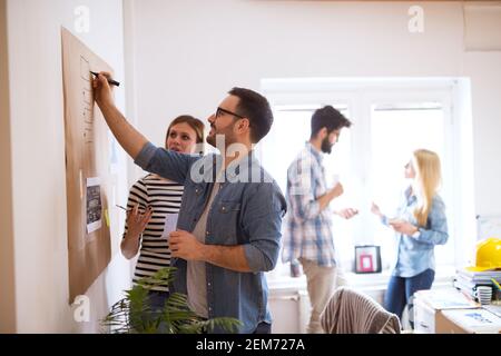 Young developers are brainstorming new algorithms how to make their software better optimized for users , while writing them down on a brownboard. Stock Photo