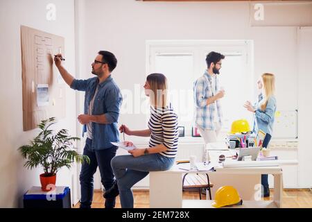 Young businessmen are developing new ideas for their future project, while their colleagues are having a coffee break in the office. Stock Photo