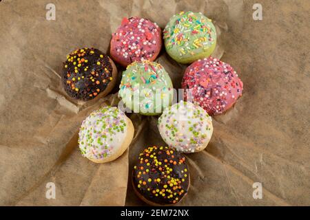 Sweet small doughnuts with sprinkles on a parchment paper Stock Photo