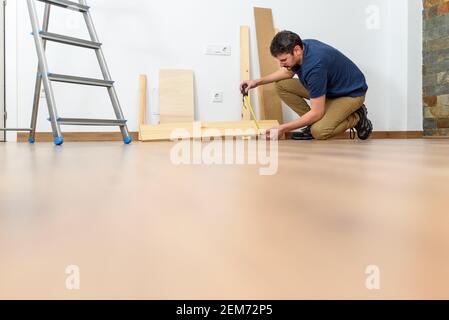 Young person doing DIY work at home. Photography at ground level. Natural day light. White wall. High quality photo. Stock Photo